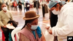 A woman gets a shot of the Sinopharm COVID-19 vaccine during vaccinations of people over age 40 inside the gym of the American Institute school in La Paz, Bolivia, June 4, 2021.