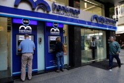 FILE - People use an ATM outside a bank, in Beirut, Lebanon, Nov. 20, 2019.
