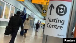 Travellers pass a sign for a COVID-19 test centre at Heathrow Airport, London, Britain, February 13, 2021. 