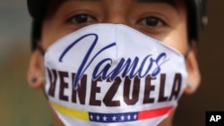 A Venezuelan migrant wearing a face face mask that reads in Spanish "Let's go Venezuela" walks toward the Venezuelan border after a lockdown ordered by the government, in Bogota, Colombia, Monday, April 6, 2020.