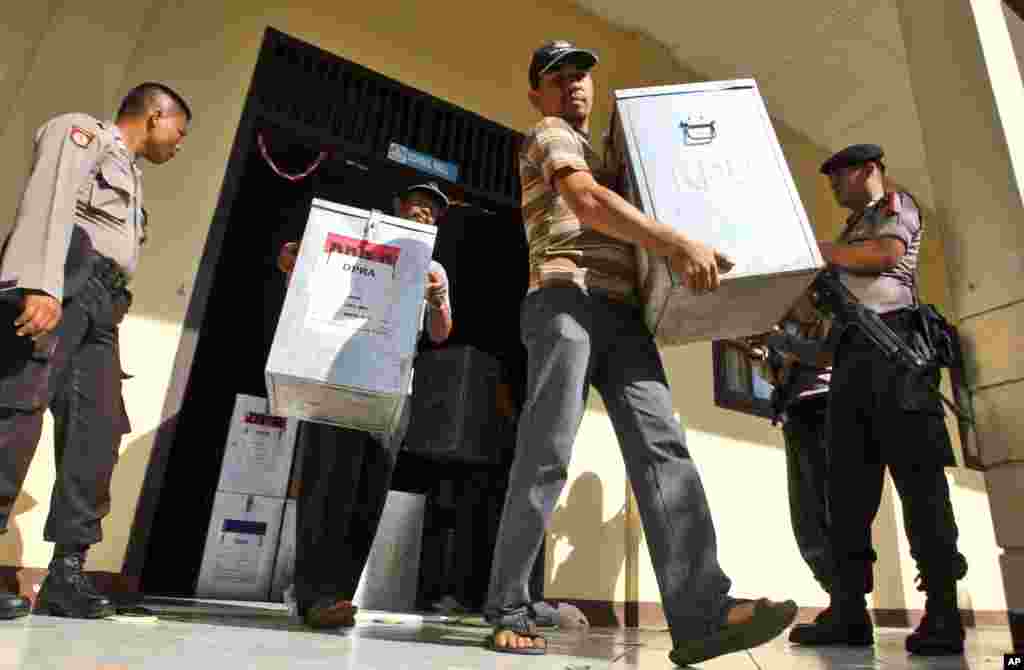Polisi bersenjata berjaga-jaga ketika seorang petugas KPU membawa kotak suara untuk didistribusikan ke TPS di kantor pemerintah daerah di Banda Aceh, Indonesia, 8 April 2014.