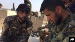 A Kurd fighter Ardal, right, and Arab fighter, Abdullah, left, who fight together with the U.S.-backed Syrian Democratic Forces (SDF), sit on their roof top position where they battle against the Islamic State militants, in Raqqa, northeast Syria., July 22, 2017.