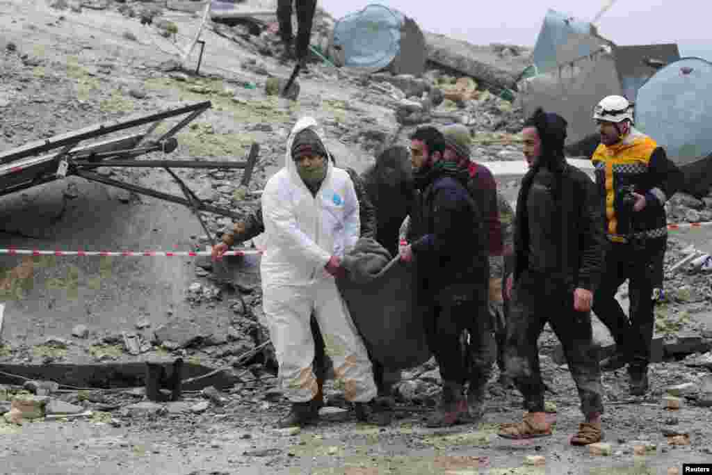 People carry a victim as rescuers search for survivors under the rubble, following an earthquake, in rebel-held town of Jandaris, Syria, Feb. 6, 2023. 