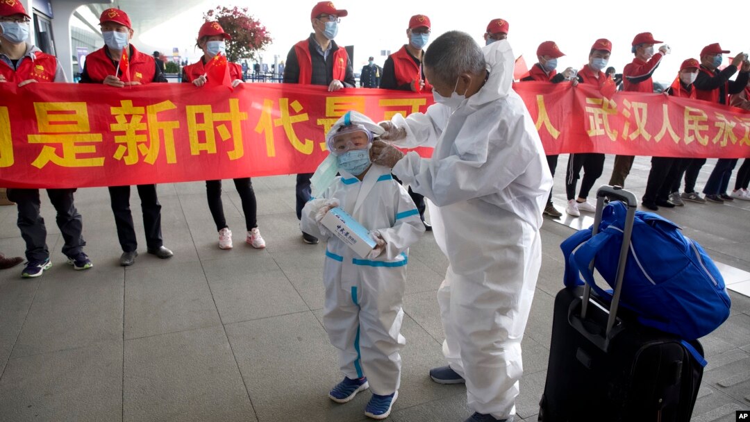 武漢解封，天河國際機場的旅客站在慶祝的標語橫幅旁。（2020年4月8日）