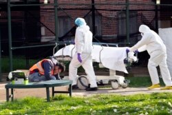 Medical personnel transport a body from a refrigerated container at Kingsbrook Jewish Medical Center, April 8, 2020, in the Brooklyn borough of New York.