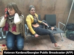 An injured woman looks on as another speaks on her mobile phone following twin blasts at Brussels airport in Zaventem, Belgium, March 22, 2016.