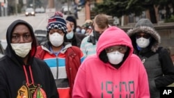FILE - Voters masked against coronavirus line up at Riverside High School for Wisconsin's primary election April 7, 2020, in Milwaukee, Wis. 