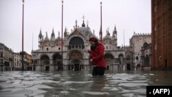 Seorang wanita melintasi alun-alun St. Mark yang dibanjiri oleh Basilika Santo Markus setelah ketinggian air pasang semalam "Alta Acqua", awal 13 November 2019 di Venesia. (Foto: AFP)