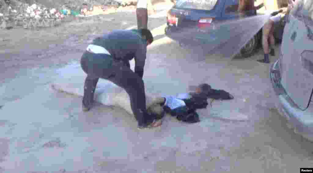 A still image taken from a video posted to a social media website on April 4, 2017, shows a man lying on the ground and being sprayed with water, said to be in the town of Khan Sheikhoun.
