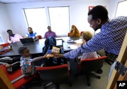 FILE - Somali immigrant leader Jamal Dar, right, who arrived in the U.S. two decades ago from Kenya, hands out snacks to a boy at a community engagement and civic language class for former Somali residents in East Portland, Oregon, July 21, 2015.