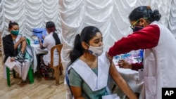 Seorang petugas kesehatan tengah menyuntik vaksin COVID-19 para remaja di sebuah sekolah di Kolkata, India, 3 Januari 2022. (AP Photo/Bikas Das)
