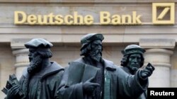 FILE - A statue stands next to the logo of Germany's Deutsche Bank in Frankfurt, Germany, Sept. 30, 2016.