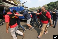 FILE - Police officers escort men arrested in a raid on a gay sauna at North Jakarta police headquarters in Jakarta, Indonesia, May 22, 2017.
