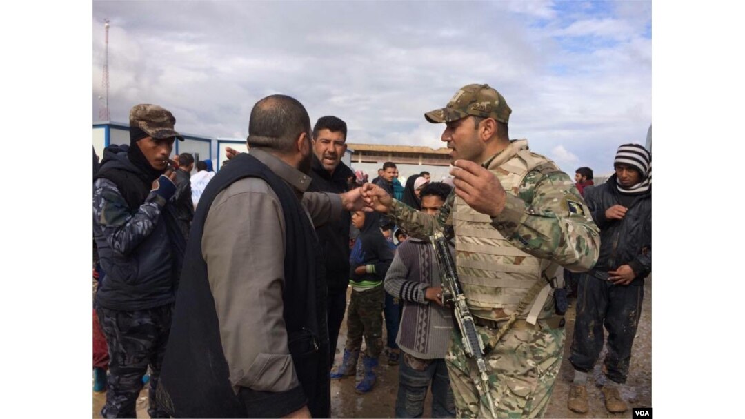 Soldiers explain security procedures intended to catch any militants trying to flee with families as they arrive at camps outside of Mosul on March 19, 2017 in Hammam Aleel, Iraq. (H.Murdock/VOA)