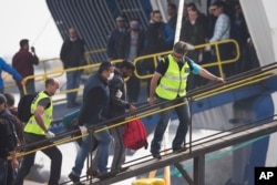Officers from the European Union’s border protection agency, Frontex, lead a migrant as they get in a ferry in the port of Mytilini, Lesbos island, Greece, April 8, 2016.