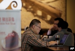 FILE - A man surfs Internet on his laptop computer at a Starbucks cafe in Beijing, Feb. 16, 2015.