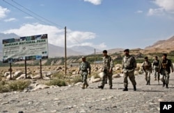 FILE - Afghan border police walk the Afghanistan side of the border with Tajikistan, in Ishkashim, Badakhshan province, far northeastern Afghanistan, Aug. 16, 2016.