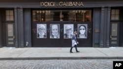 A man wearing a face mask to protect against the coronavirus walks past a closed Dolce & Gabbana store, Thursday, May 7, 2020, in the Soho neighborhood of Manhattan in New York. Nearly 3.2 million laid-off workers applied for unemployment benefits…