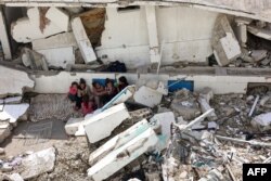 Anak-anak Palestina yang terlantar duduk di tengah reruntuhan bangunan yang hancur di distrik Nasser, Kota Gaza, di Jalur Gaza utara pada 25 Oktober 2024. (Foto: AFP)