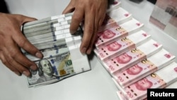 資料照：中國一家銀行的僱員在點數美元和人民幣。