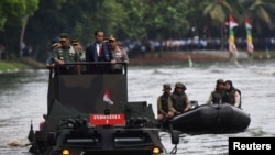 Presiden Joko Widodo, bersama Panglima TNI Jenderal Gatot Nurmantyo (kiri) dan Kapolri Jenderal Tito Karnavian (kanan), menyeberangi danau di Jakarta dengan memakai kendaraan amfibi militer Anoa 2 (16/1). 