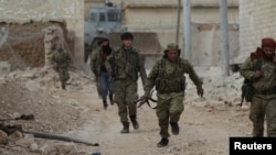 Seorang pejuang pemberontak berlari dengan membawa senjata di kota al-Bab, pinggiranSuriah utara, Suriah, 26 Januari 2017. (REUTERS/Khalil Ashawi)