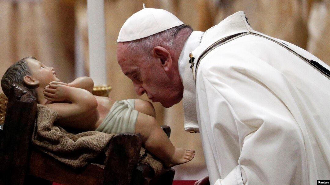 Pope Francis kisses a statue of baby Jesus as he leads the Christmas Eve mass in St. Peter's Basilica at the Vatican, Dec. 24, 2019.