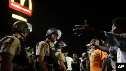 FILE - Officers and protesters face off along West Florissant Avenue in Ferguson, Mo., Aug. 10, 2015. The city and the U.S. Justice Department have reached an agreement over police reform.