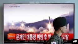 Seorang tentara Korea Selatan berjalan melalui sebuah program berita TV yang menunjukkan citra rudal yang diluncurkan uji coba oleh Korea Utara, di Stasiun Kereta di Seoul, Korea Selatan, 14 Mei 2017.