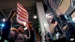 Seorang demonstran menantang polisi di pintu masuk Terminal 4 di Bandar Udara Internasional John F. Kennedy di New York (28/1). (AP/Craig Ruttle)