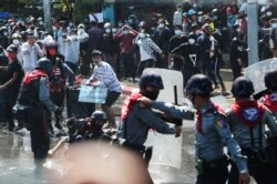 FILE - Protesters run after police fire warning shots and use water cannons to disperse them during a protest in Mandalay, Myanmar, Feb. 9, 2021.