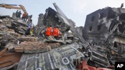 Para penyelidik memeriksa puing-puing pesawat Hercules milik Angkatan Udara yang jatuh di Medan (1/7). (AP/Binsar Bakkara)