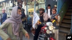 FILE - A Taliban fighter sits on his motorcycle adorned with a Taliban flag in a street in Kunduz, Afghanistan. 