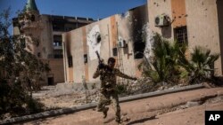 FILE - A fighter of the Libyan forces, affiliated with the Tripoli government, runs for cover while fighting against Islamic State positions in Sirte, Libya, Sept. 22, 2016.