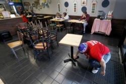 Restaurant manager Natalie Marquez sanitizes tables and stacks chairs in Chicago, March 16, 2020.