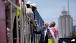 Presidente dos Estados Unidos Joe Biden e o Diretor de Operações da Lobito Atlantic Railway, Nicolas Gregoire, falam com trabalhadores no Porto do Lobito, Angola, 4 dezembro 2024