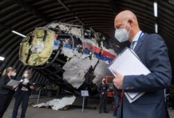 Hakim Ketua Hendrik Steenhuis, kanan, dan hakim pengadilan serta pengacara lainnya melihat puing-puing pesawat Malaysia Airlines MH17 yang direkonstruksi, di pangkalan militer Gilze-Rijen, Belanda selatan, Rabu, 26 Mei 2021. (Foto: AP)