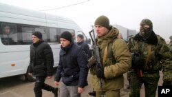 Tawanan perang asal Ukraina dikawal tentara-tentara kelompok separatis dukungan Rusia, berjalan ke bus-bus untuk proses pertukaran tahanan di Horlivka, timur Ukraina, 29 Desember 2019.