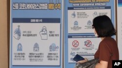 在韩国首尔景福宫，戴着口罩的行人走在预防冠状病毒预防措施的横幅前。（2020年8月16日）