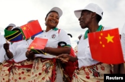 FILE - Tanzanian women wait to welcome China's President Xi Jinping when he disembarks at Julius Nyerere International Airport.