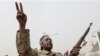 An armed Libyan rebel chants anti-Gadhafi slogans during a rally in Benghazi, March 13, 2011