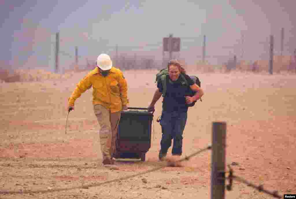 A member of the media helps a resident as firefighters and aircraft battle the Hughes Fire near Castaic Lake, north of Santa Clarita, California, Jan. 22, 2025.
