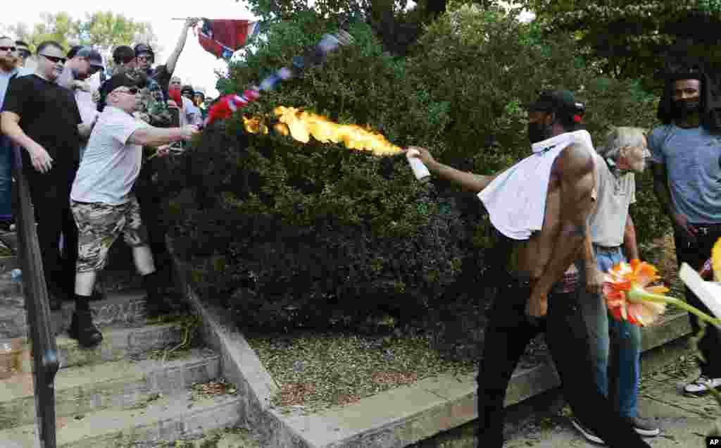 A counter demonstrator uses a lighted spray can against a white nationalist demonstrator at the entrance to Lee Park in Charlottesville, Va., Aug. 12, 2017.