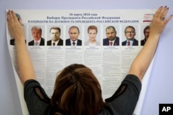 A polling station employee hangs a list of candidates for the 2018 Russian presidential election during preparations for the election at a polling station in St.Petersburg, Russia, March 16, 2018. The presidential elections will be held in Russia March 18
