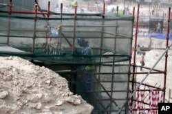 In this photo taken during a government organized media tour, a foreign worker climbs scaffolding at the Al-Wakra Stadium that is under construction for the 2022 World Cup, in Doha, Qatar, May 4, 2015.