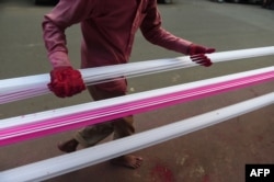 Seorang pria melapisi benang untuk menerbangkan layang-layang dengan bubuk kaca berwarna menjelang 'Uttarayan' atau festival Layang-layang, di Ahmedabad pada 13 Desember 2020. (Foto: AFP)