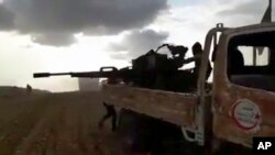 Gambar cuplikan dari rekaman video yang diberikan oleh Jaringan Berita Baladi, media milik oposisi Suriah menunjukkan para pejuang oposisi Suriah menembakkan senjatanya dalam bentrokan dengan pasukan Suriah dan penembak pro-pemerintah (9/2). Al-Bab, Provinsi Aleppo, Suriah. (foto: Baladi News Network, via AP)