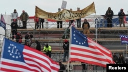 Para pendukung Presiden AS Donald Trump membentangkan spanduk bertuliskan "Kami adalah Rakyat," bendera Three Percenters, dan bendera 13 bintang Betsy Ross, berkumpul di depan Gedung Kongres AS, di Washington, 6 Januari 2021. 