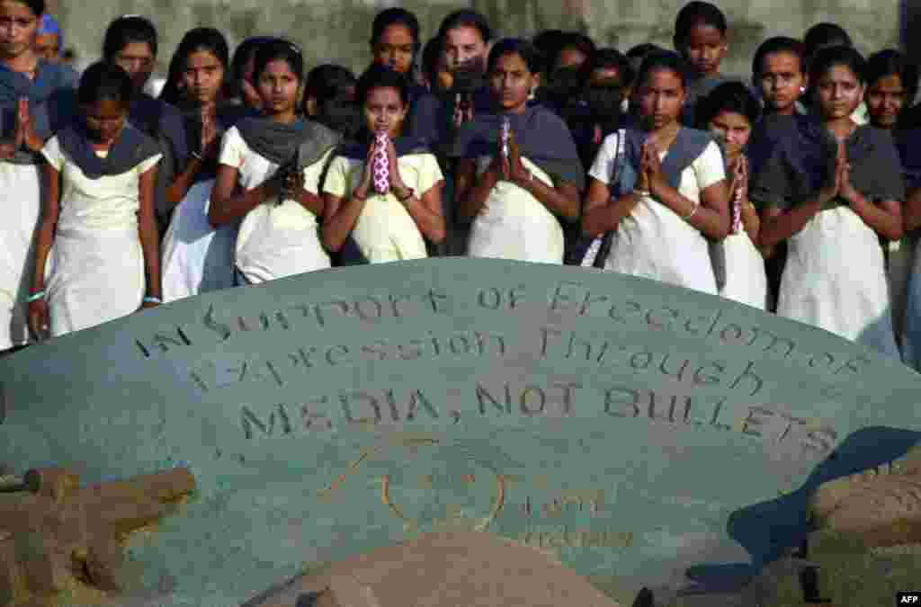 Indian students offer prayers alongside a sand sculpture paying tribute to the victims of the attack on French satirical newspaper Charlie Hebdoat, at Juhu Beach in Mumbai, Jan. 9, 2015.