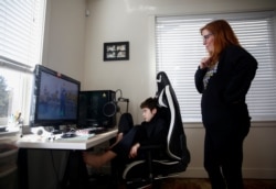 Tracey Pucci dan putranya, Foxton Harding, 12, menonton video latihan yang dibuat oleh para guru Foxton di Northshore Middle School ketika sekolah beralih ke pembelajaran online selama dua minggu di rumah mereka di Bothell, Washington, AS, 11 Maret 2020.
